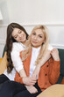© diignat - Beautiful mother and adult daughter hugging portrait close up, sitting on couch at home, smiling woman embracing mum, spending leisure time together, two generations good relationship
