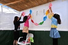 Jewish Family Decorating The Interior Of A Sukkah With Colourful Traditional  Artwork