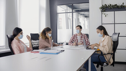 young business people wearing protective masks during work meeting, pandemic