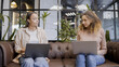 © Synthex - Two women talking, typing on laptops in office, female IT specialists at work