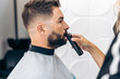© Samuel Perales - Hairdresser grooming the moustache of a man with an electric razor in a barber shop