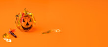 A Pumpkin-shaped Pot Is Filled With Marmalade Worms On An Orange Background. The Funny Concept Of Halloween.