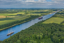 Aerial View Of Kiel Canal With Container Ship And  Traditional Sailing Vessel.Container Cargo Ship And Tall Ship On The Kiel Canal Between Baltic Sea And North Sea Schleswig Holstein, Germany.