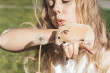 Fototapeta  - Girl with a hamster in nature. Cheerful happy child girl with pet hamster plays in the backyard of the house in summer. Love, care, tenderness concept.
