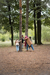 Wall Mural - Muslim family playing near trees in autumn park