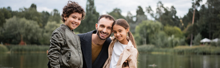 Canvas Print - Arabian father hugging kids in park, banner