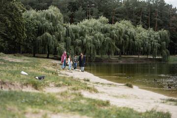 Canvas Print - Muslim family with kids walking near lake in autumn park