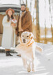 © Yuliia - Young family walks with a dog in the winter forest on vacation.