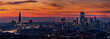 Wide panoramic view of the illuminated skyline of London, United Kingdom, during evening time with orange sky