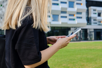 Wall Mural - a girl with a smartphone in her hands is standing near the business center. businesswoman sends a te