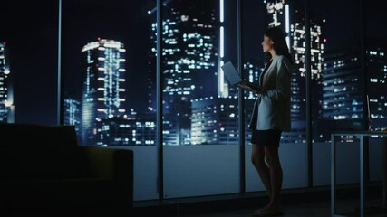 Wall Mural - Big City Modern Office at Night: Successful Young Businesswoman Standing and Using Laptop. Beautiful Female Digital Entrepreneur Thinking of Investment Strategy for e-Commerce Project. Arc Full Shot