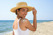 © New Africa - Beautiful young woman with sun protection cream on shoulder at beach