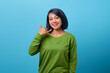 Beautiful Asian woman showing phone call gesture on blue background