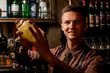 © fesenko - portrait of smiling man bartender holding glassy shaker in his hands and shakes it