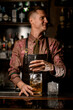 © fesenko - hand of man bartender holds long bar spoon and gently stirring cold drink into mixing cup