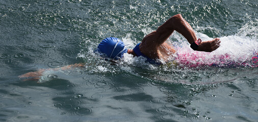 Wall Mural - Man swimmer swimming crawl in blue sea, race for triathlon