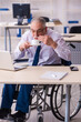 © Elnur - Old male employee in wheel-chair drinking coffee during break