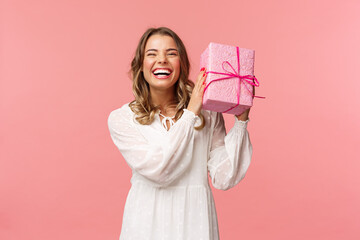 holidays, celebration and women concept. portrait of happy charismatic blond girl shaking gift box w