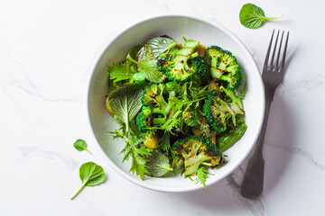 Wall Mural - Green salad with grilled broccoli and olives in white bowl. Vegan food, detox, healthy food concept