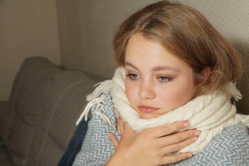 Woman sneezes in white tissue.  Young blonde woman wrapped in warm blanket, sneezes, has flu.