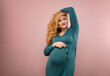 © rubchikova - Portrait of a smiling pregnant woman in a green dress