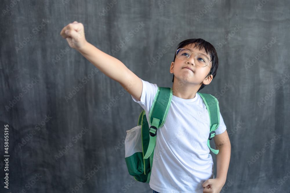 Little Asian boy wearing glasses with school bag and raising his hands ...