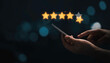 © Dilok - Hand holding and using smartphone with virtual five golden stars with glowing light for the best customer client evaluation score after use product and service concept.