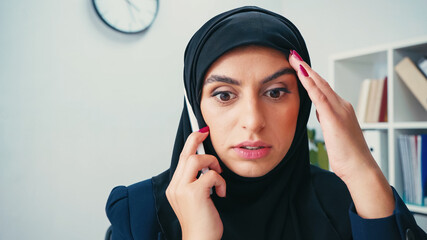 Wall Mural - stunned muslim businesswoman in hijab talking on cellphone in office