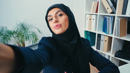 Wall Mural - young muslim businesswoman pouting lips while taking selfie