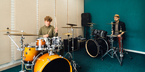 Wall Mural - Boy learns to play the drum kit. Music lesson with teacher.