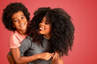 © Brastock Images - Portrait of young African American mother with toddler son. Red background. Brazilian family.