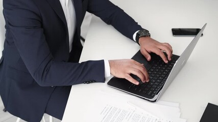 Finish work. Office man. Business communication. Unrecognizable stylish guy in elegant suit typing laptop sitting table with documents light room interior.