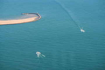 Aerial view of two motor boats passing one another on the calm blue water of Lake Michigan near North Avenue Beach in Chicago on a sunny summer morning.