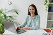 © ViDi Studio - Young happy confident employee operator business woman in set microphone headset blue shirt for helpline assistance sit work at call center workplace desk with laptop pc computer typing office indoor