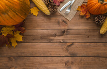 Autumn Flat Lay Composition. Pumpkins, Corncobs (corn On The Cob), Fall Leaves, Cones, Fork And Knife On A Jute Material, For Thanksgiving Dinner. Copy Space On Wooden Background.
