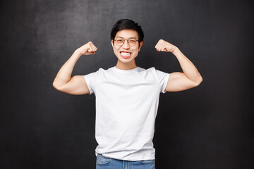 Sport, athletes and olimpics concept. Cheerful and strong young handsome boyfriend bragging with his strength, got fit for summer, flex biceps and smiling satisfied, black background