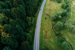 Cars moving on countryside road through mountains covered with pine tree forest, aerial view. Car trip at summer vacation