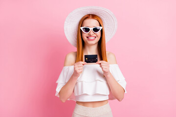 Photo of charming pretty young woman hold hands credit card smile good mood isolated on pink color background