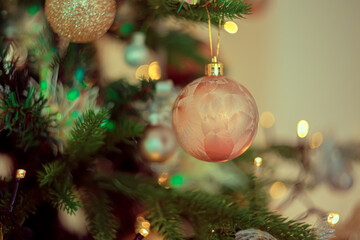 Wall Mural - Gold festive decorations ball on the Christmas tree and beautiful yellow bokeh of glowing garland. Dark background