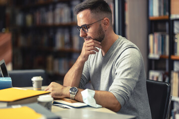 Wall Mural - Male student studying in campus library during quarantine.