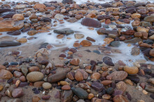 Soft Blue Waves Coming Through Colourful Pebbles At The Beach In Adelaide, South Australia