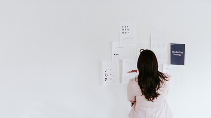 Businesswoman planning marketing strategy on a wall