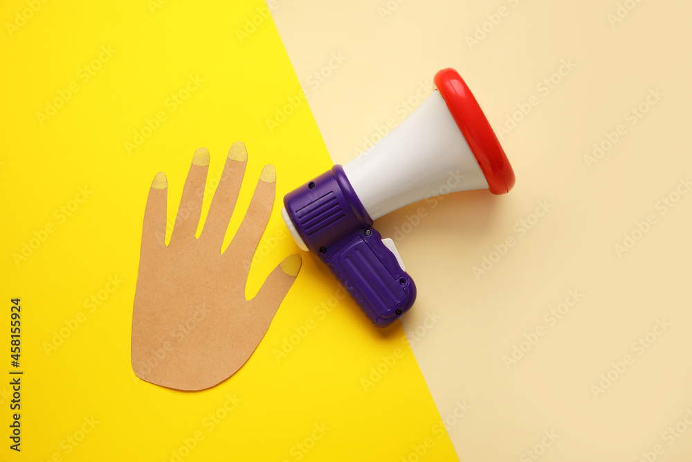 Toy megaphone and paper hand on color background