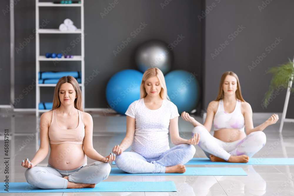 Young pregnant women practicing yoga at gym