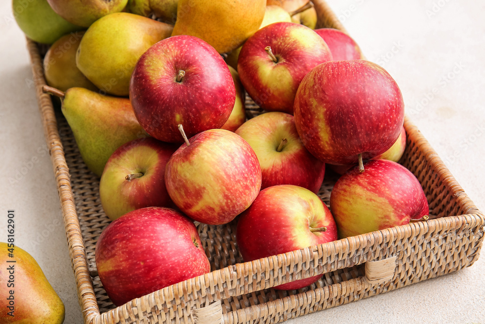 Tray with ripe pears and apples on light background, closeup
