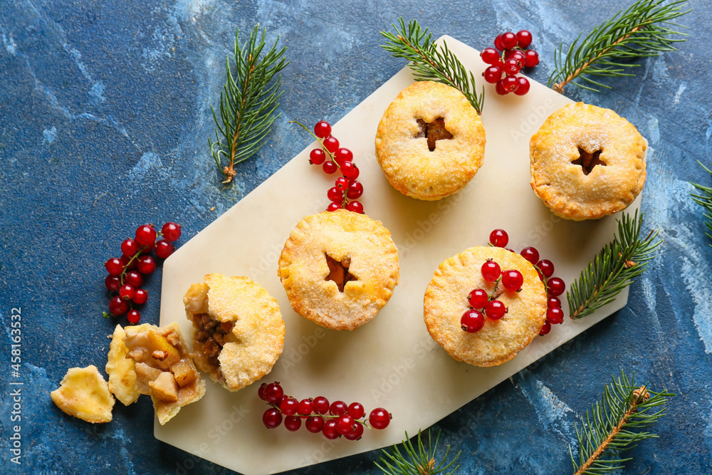 Board with tasty mince pies on color background