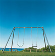© Austockphoto - Playground swing set with blue sky and ocean background