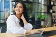 © Mallika - Beautiful Asian woman using laptop in cafe, Asian woman in casual shirt working at coffee shop.