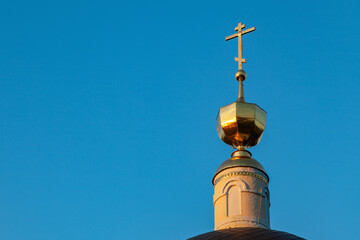 Gilded dome and cross of the Orthodox Church against the background of a clear blue sky