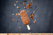 Ice Cream Bar with chocolate coating and almonds in a studio shot with bits of chocolate and almonds falling over it